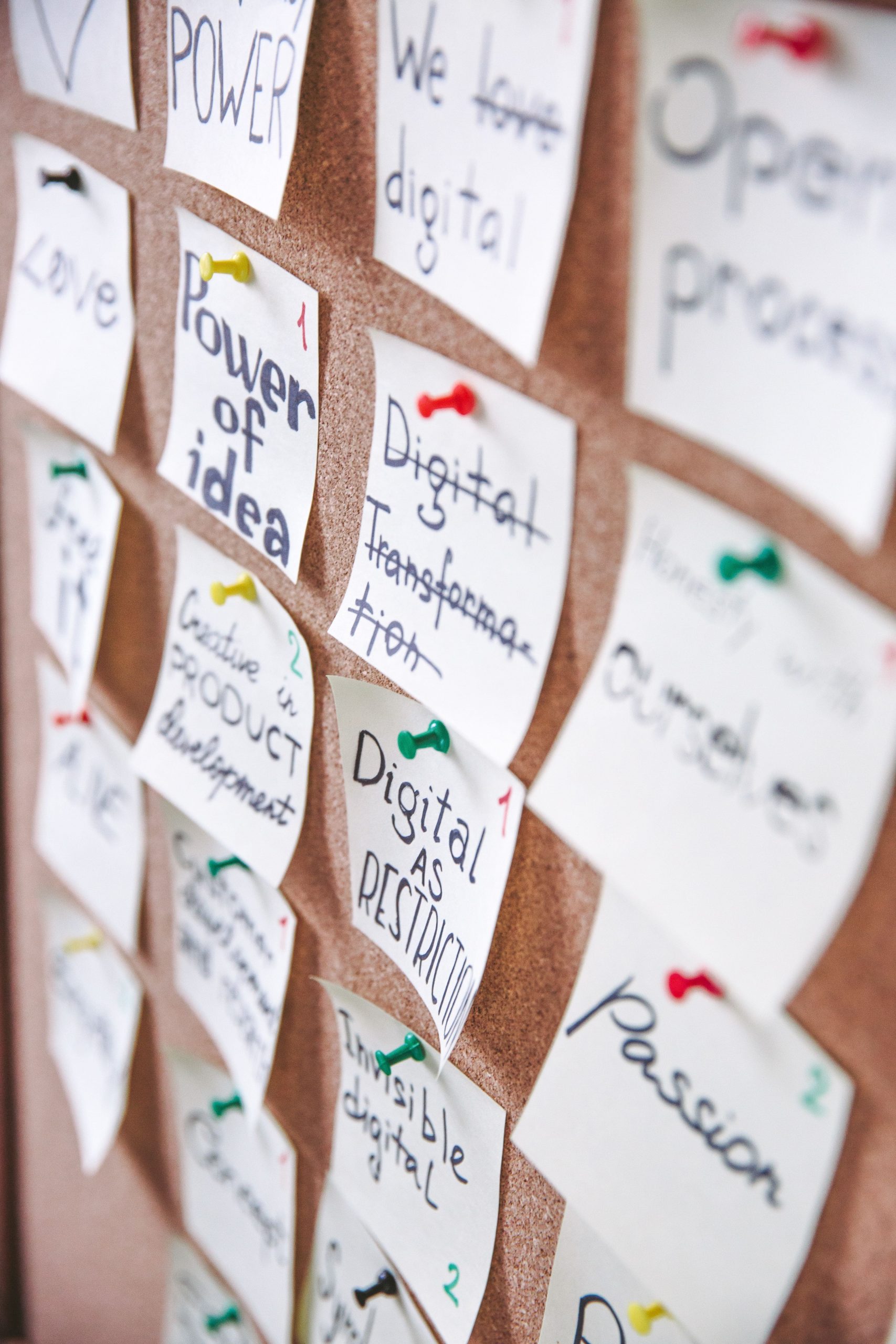 Corkboard filled with handwritten sticky notes detailing startup core values, business principles, and product development ideas.